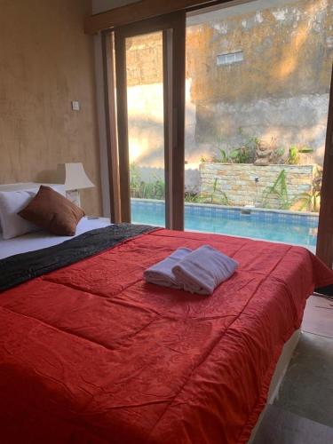 a bedroom with a red bed and a large window at Pranajayaloka private villa in Tejakula