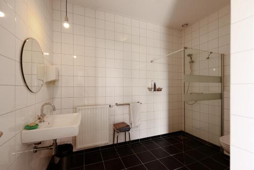 a white bathroom with a sink and a shower at Historische Boerderij FAMILIEKAMER in Heinkensand