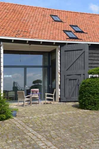 a patio with a barn with two chairs and a table at Historische Boerderij FAMILIEKAMER in Heinkensand