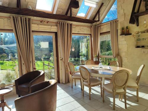 a dining room with a table and chairs and windows at La Vendemiere - Maison d'hôtes de charme et de caractère, Bretagne, Côtes d'Armror in Pont-Melvez