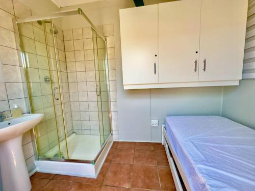 a bathroom with a shower and a bed and a sink at The Perfect Hartenbos Holiday Home in Mossel Bay