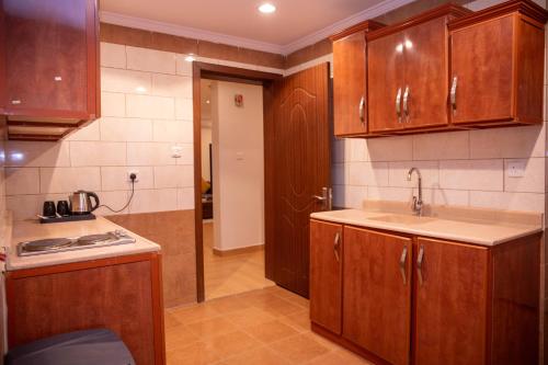 a kitchen with wooden cabinets and a sink at Golden Suites in Al Jubail