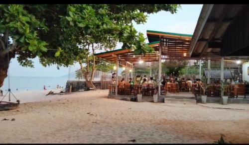a group of people sitting at a restaurant on the beach at Nadan Beach House in Ban Thung O