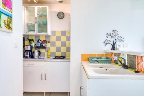 eine Küche mit weißen Schränken und einem Waschbecken in der Unterkunft Maisonnette 37 m2 in Lattes