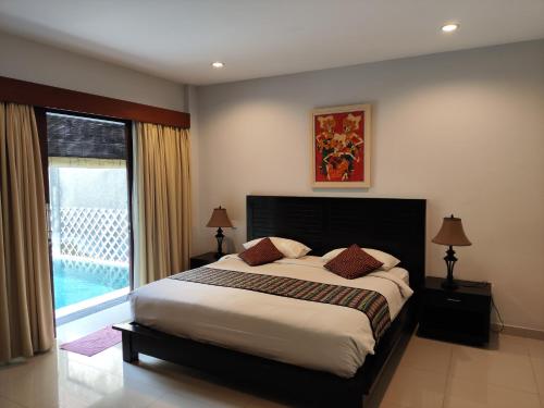 a bedroom with a bed and a large window at Villa Lovecho in Canggu