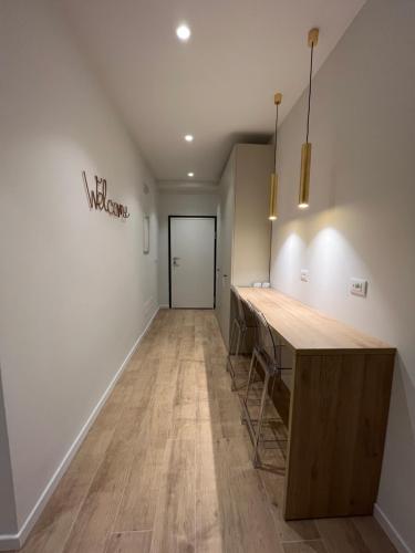 a hallway with white walls and wooden tables and a door at Calari Rooms - Affittacamere in Bologna
