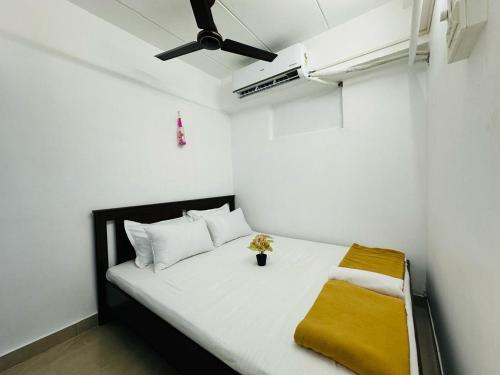 um pequeno quarto com uma cama branca e um cobertor amarelo em 1BR Apartment Parel em Mumbai