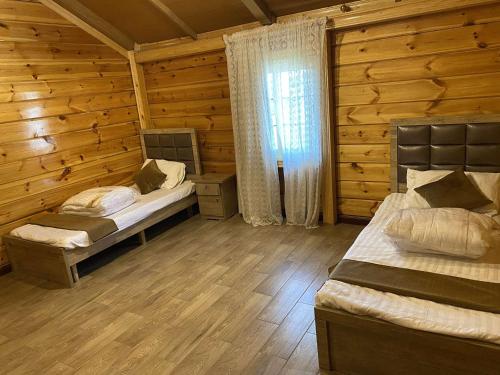 1 dormitorio con 2 camas en una cabaña de madera en القصر الريفي en Al Khafji