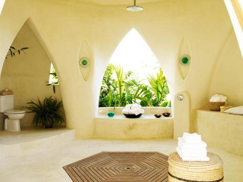 a bathroom with a large window and a bath tub at Kilindi Zanzibar in Kendwa