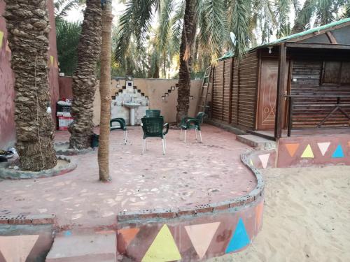 a patio with palm trees and a table and chairs at Omar Oasis in Siwa