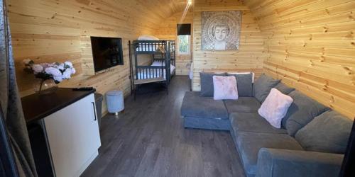 a living room with a couch in a log cabin at Dog Friendly Stagecoach Glamping Pod with Hot Tub in Kingsley