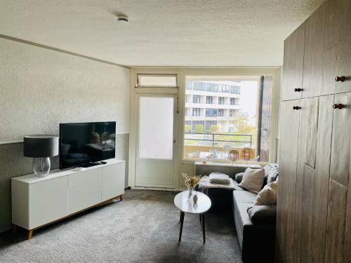 ein Wohnzimmer mit einem Sofa, einem TV und einem Tisch in der Unterkunft Strandhafer in Wendtorf