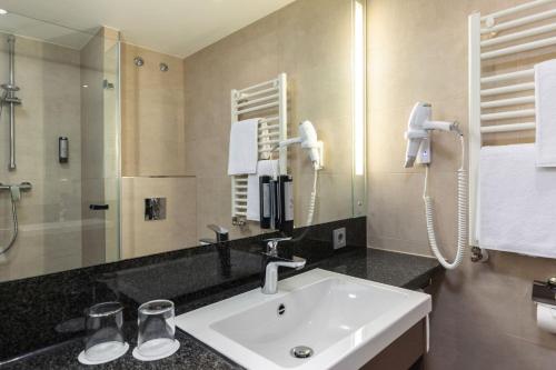 a bathroom with a sink and a mirror at IntercityHotel Dresden in Dresden