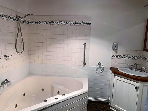a white bathroom with a tub and a sink at Apollo Bay Cottages- Marriners in Marengo