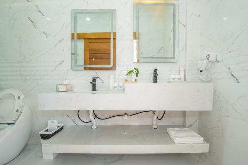 een witte badkamer met een wastafel en een spiegel bij V Pool Villa Sattahip in Sattahip