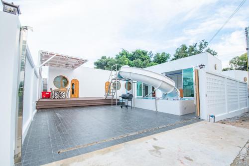 a white house with a slide in the backyard at V Pool Villa Sattahip in Sattahip