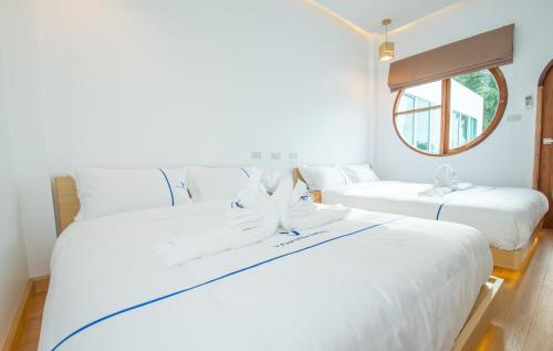 2 witte bedden in een kamer met een raam bij V Pool Villa Sattahip in Sattahip