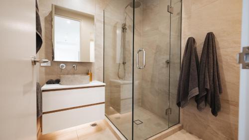 a bathroom with a shower with a sink and a mirror at Beautiful urban apartment 3 in Nelson