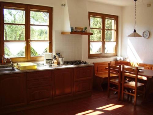 een keuken met een wastafel en een tafel met stoelen bij Casa Le Basse - Vetulonia in Gavorrano
