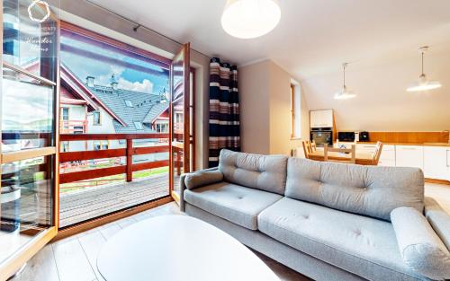 a living room with a couch and a large window at Wonder Home - Domki górskie na osiedlu dozorowanym, z kominkami i placem zabaw in Karpacz