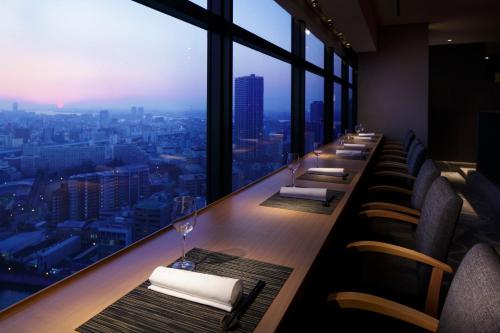 a long bar with a view of a city at RIHGA Royal Hotel Osaka, Vignette Collection by IHG in Osaka