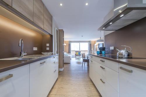 a kitchen with white cabinets and a living room at Les Chalets Du Jardin Alpin in Val dʼIsère
