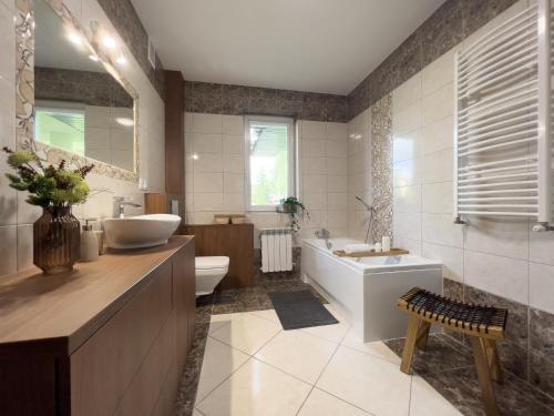 La salle de bains est pourvue d'une baignoire, d'un lavabo et de toilettes. dans l'établissement Garden House - OSTOYA, à Jasionka