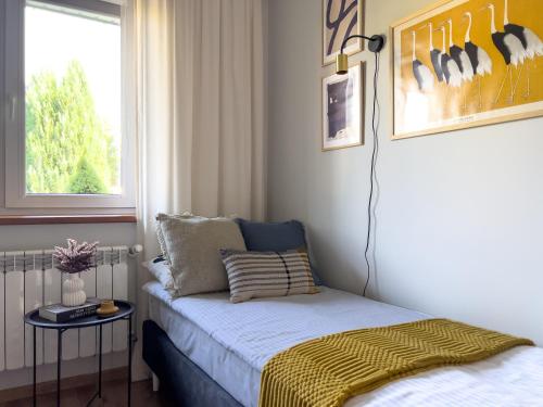 a small bedroom with a bed and a window at Garden House - OSTOYA in Jasionka