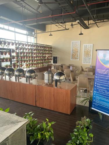 een wachtkamer met tafels en stoelen en een bord bij Daima Suites Margonda in Perhentian Pondoktjina