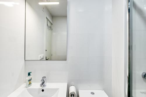 a white bathroom with a sink and a mirror at Lago Sant Mauricio in Empuriabrava