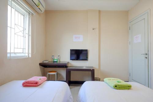 two beds in a room with a desk and a tv at RedDoorz at Jalan Emmy Saelan Palu in Palu