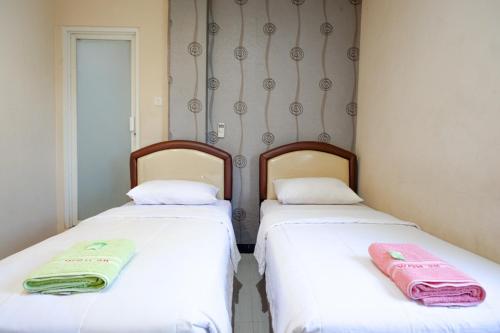 two beds sitting next to each other in a room at RedDoorz at Jalan Emmy Saelan Palu in Palu