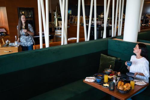 two women standing in a restaurant with a table with food at Spa Resort Styria- ADULTS ONLY in Bad Waltersdorf