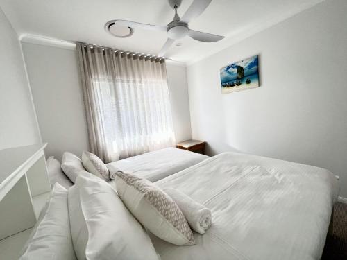 a white bedroom with two beds and a window at Luxury 4 bedroom waterfront holiday home on the Sunshine Coast in Parrearra