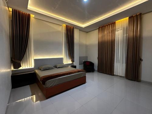 Grands Orchid Hotel في Lahat: غرفة نوم بسرير ونوافذ مع ستائر