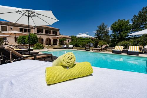 a yellow towel on a table next to a swimming pool at Mon Ventoux - Cozyhotes in Sault-de-Vaucluse