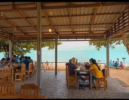 a group of people sitting at tables on the beach at Nadan Beach House in Ban Thung O