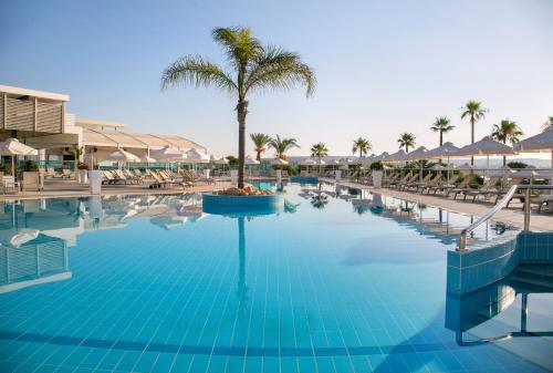 a pool at a resort with palm trees and umbrellas at Asterias Beach Hotel in Ayia Napa