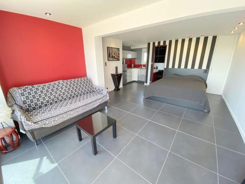 une chambre avec un lit et un mur rouge dans l'établissement Studio 383, Port Nature 3 au village naturiste, au Cap d'Agde