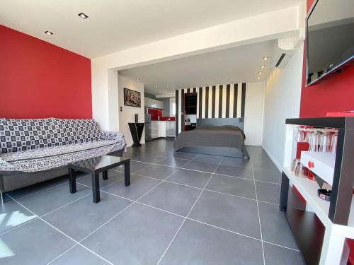 une chambre avec deux lits et un mur rouge dans l'établissement Studio 383, Port Nature 3 au village naturiste, au Cap d'Agde