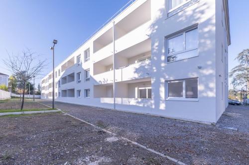 an empty parking lot next to a white building at OVELIA Andrézieux-Bouthéon - Les Demeures du Forez in Andrézieux-Bouthéon