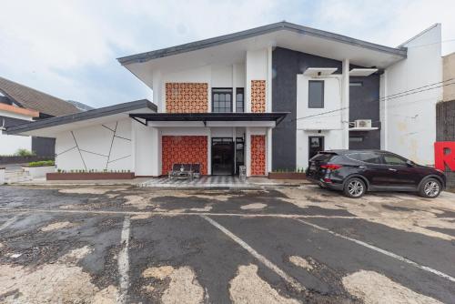 a house with a car parked in a parking lot at RedDoorz near Taman Kota Lapang Merdeka Sukabumi in Sukabumi