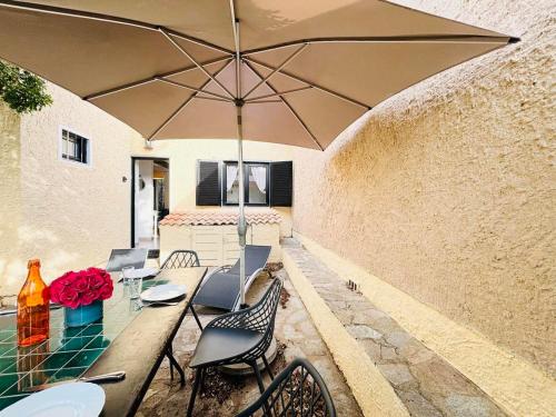 un patio avec des chaises et une table avec un parasol dans l'établissement Appartement Solane 4 Lumio, à Lumio
