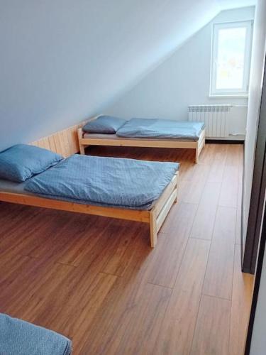 two beds in a room with a wooden floor at Domek u Anitki i Nikosia in Jeleśnia