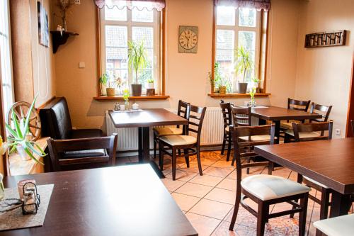 a restaurant with wooden tables and chairs and windows at Landhaus Müden in Faßberg