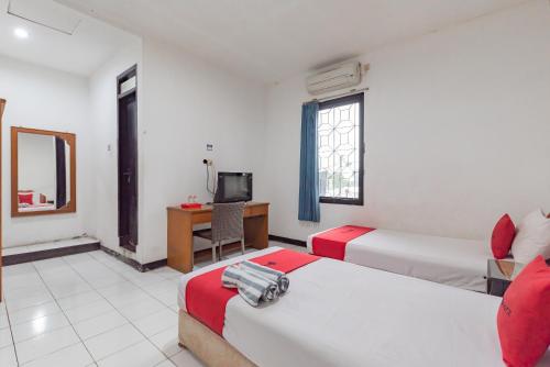 a hotel room with two beds and a television at RedDoorz near Taman Kota Lapang Merdeka Sukabumi in Sukabumi