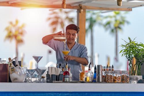 a man is making a drink at a bar at voco Dubai Monaco, the Heart of Europe by IHG in Dubai