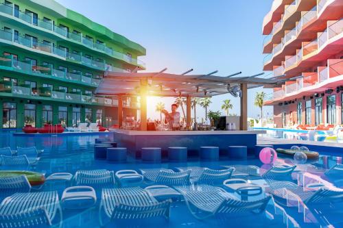 a resort with a pool with chairs and a bar at voco Dubai Monaco, the Heart of Europe by IHG in Dubai