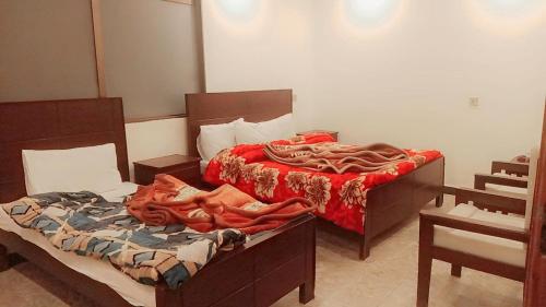 1 dormitorio con 2 camas con sábanas rojas en The Lavish Inn en Murree