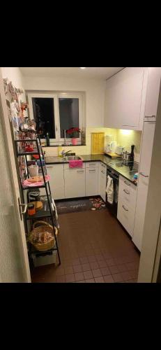 cocina con armarios blancos y suelo de baldosa en Le bijou du 3ème arrondissement en Zúrich